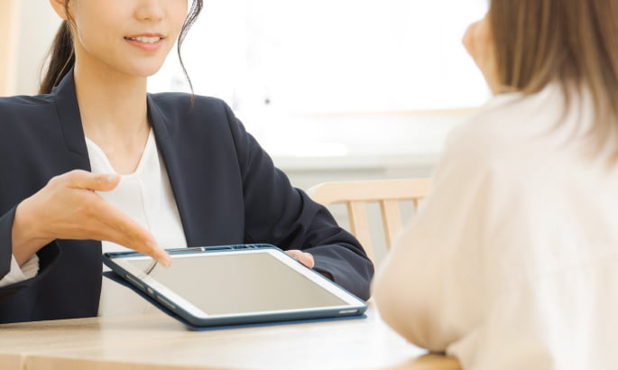 DVCリセールの費用について説明する日本人女性スタッフの画像